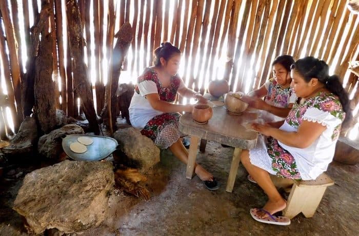 women making tortillas by hand in a mayan village near coba