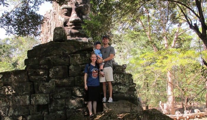The family at the north gate of angkor wat, siem reap's most famous ruined temple.