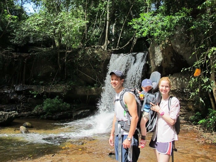 two parents and a toddler hiking to a waterfall in siem reap