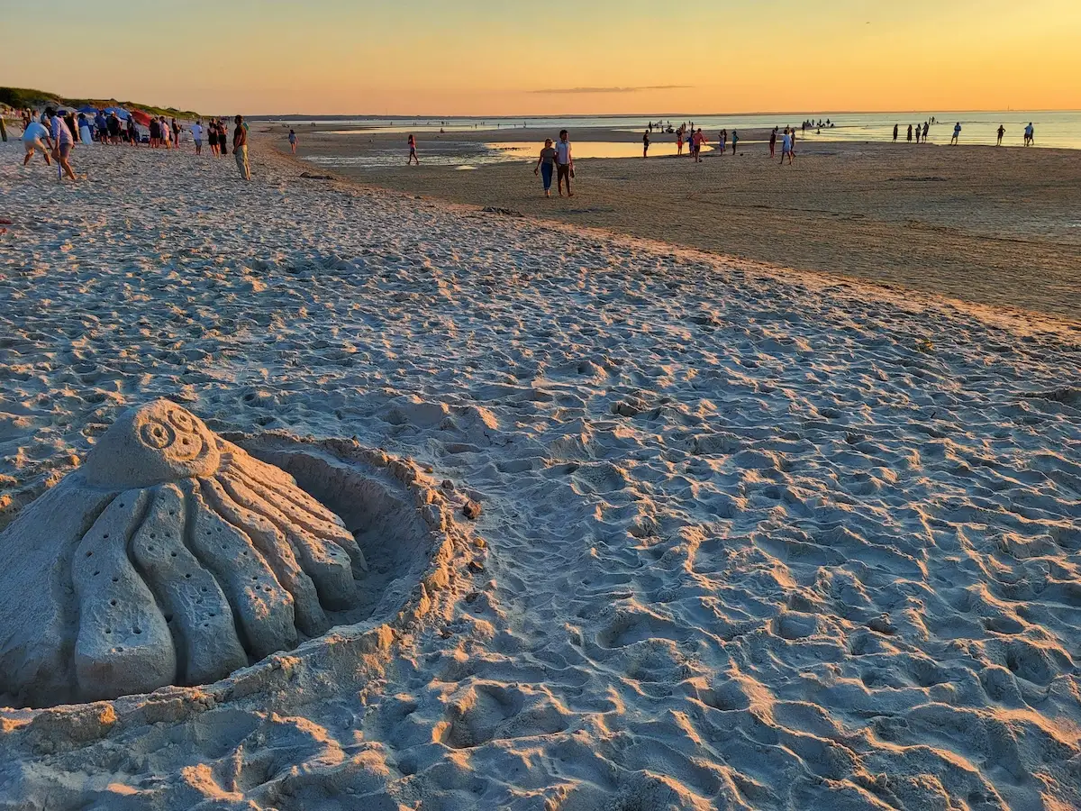 Cape Cod: 11 Fun, Cheap & Easy Summer Things To Do With Kids: Families frolic on Mayflower Beach behind an octopus sanctuary sculpture.