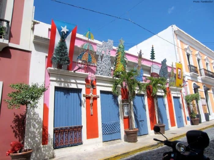 A typical street in old san juan with brightly colored houses and christmas type decorations.