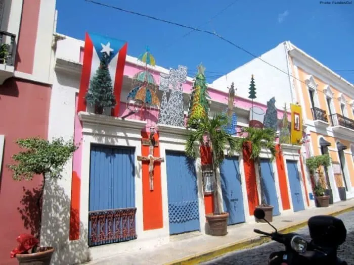 a typical street in old san juan with brightly colored houses and christmas type decorations.