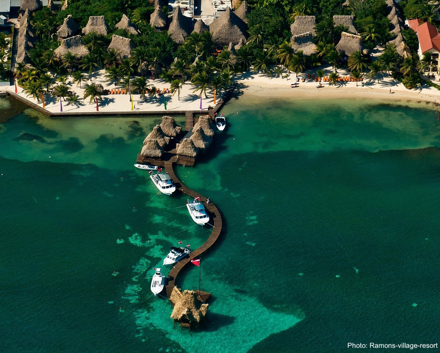 Ramon's village resort has a dock that winds into clear green water from a sandy beach.