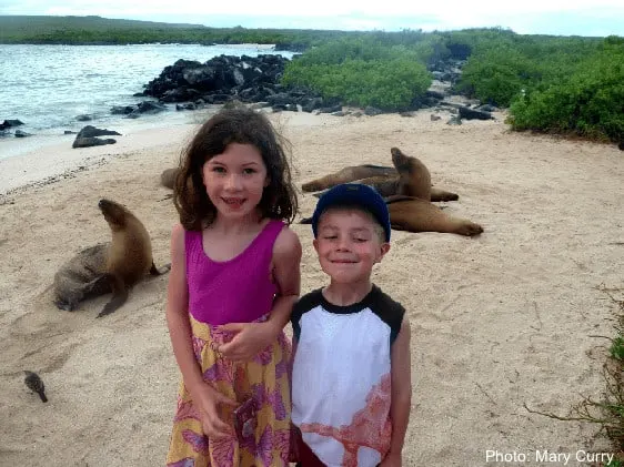 kids mugging in front ot eals on a galapagos beach