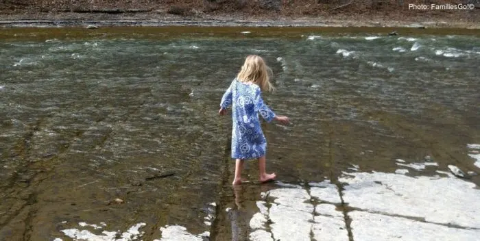 seasons change quickly in ithaca. here a girl splashes in water with snow still on the ground.