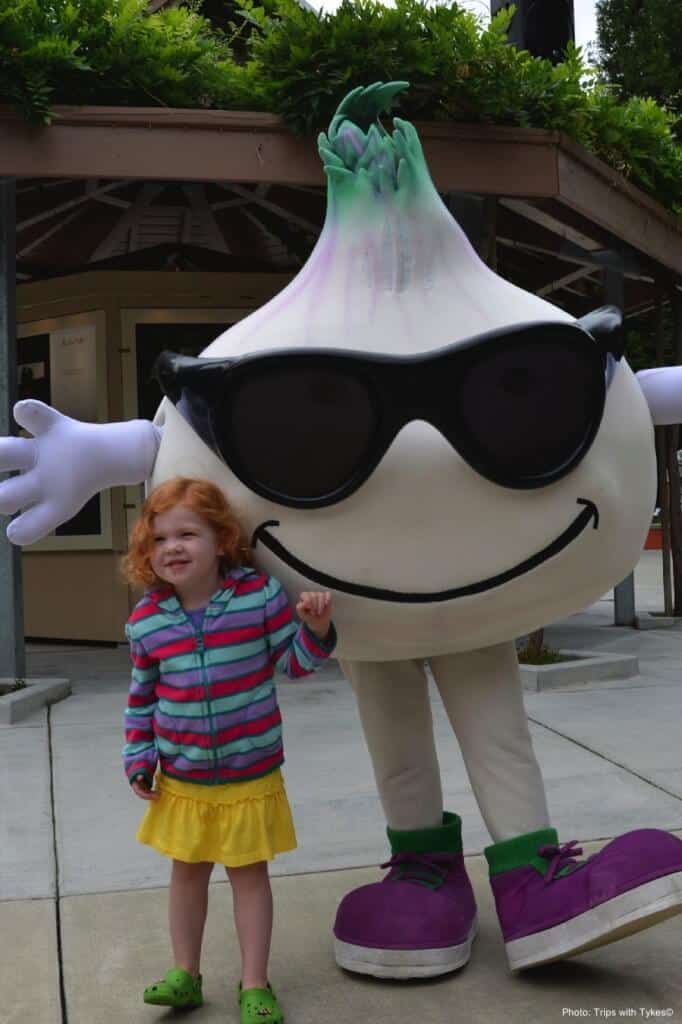 a girl making friends wih a head of garlic with shades and a mohawk at the garlic festival