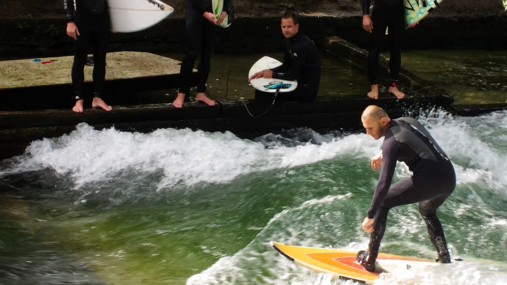 Munich: 10+ Things To Do &Amp; See That Your Whole Family Will Love A surfer balances his board in the eisbach river in munich. Watching the surfers is a fun thing to do with kids