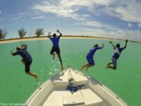 4 boys jumping off a boat in turks & caicos