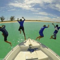 4 boys jumping off a boat in Turks & Caicos