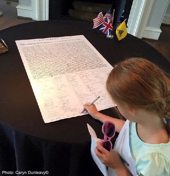 A girl signs the declaration of independence