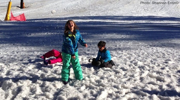 ski trips with kids are better when you take breaks for fun. here three kids goof around in the snow.