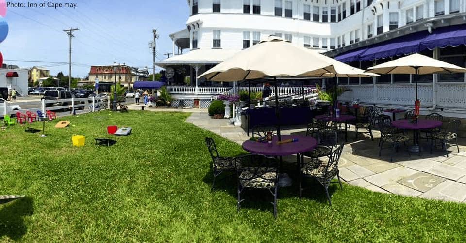 the grass and stone patio with umbrella-shaded tables at the inn at cape may