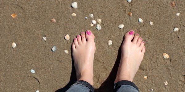Feet on a beach with pink toenails