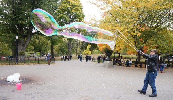 A man makes giant bubbles in new york city's central park.