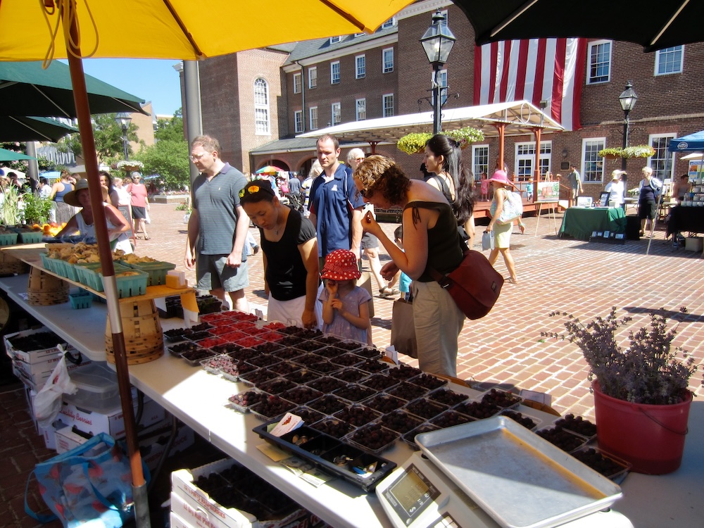 A mom and daughter sample blackberries and raspberries at the alexandria farmers market.