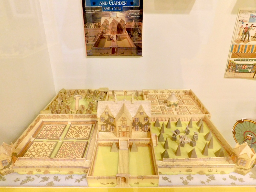 A model of an english mansion and its grounds with the house, outbuildings, lawns trees, hedge rows and garden mazes all made from paper.