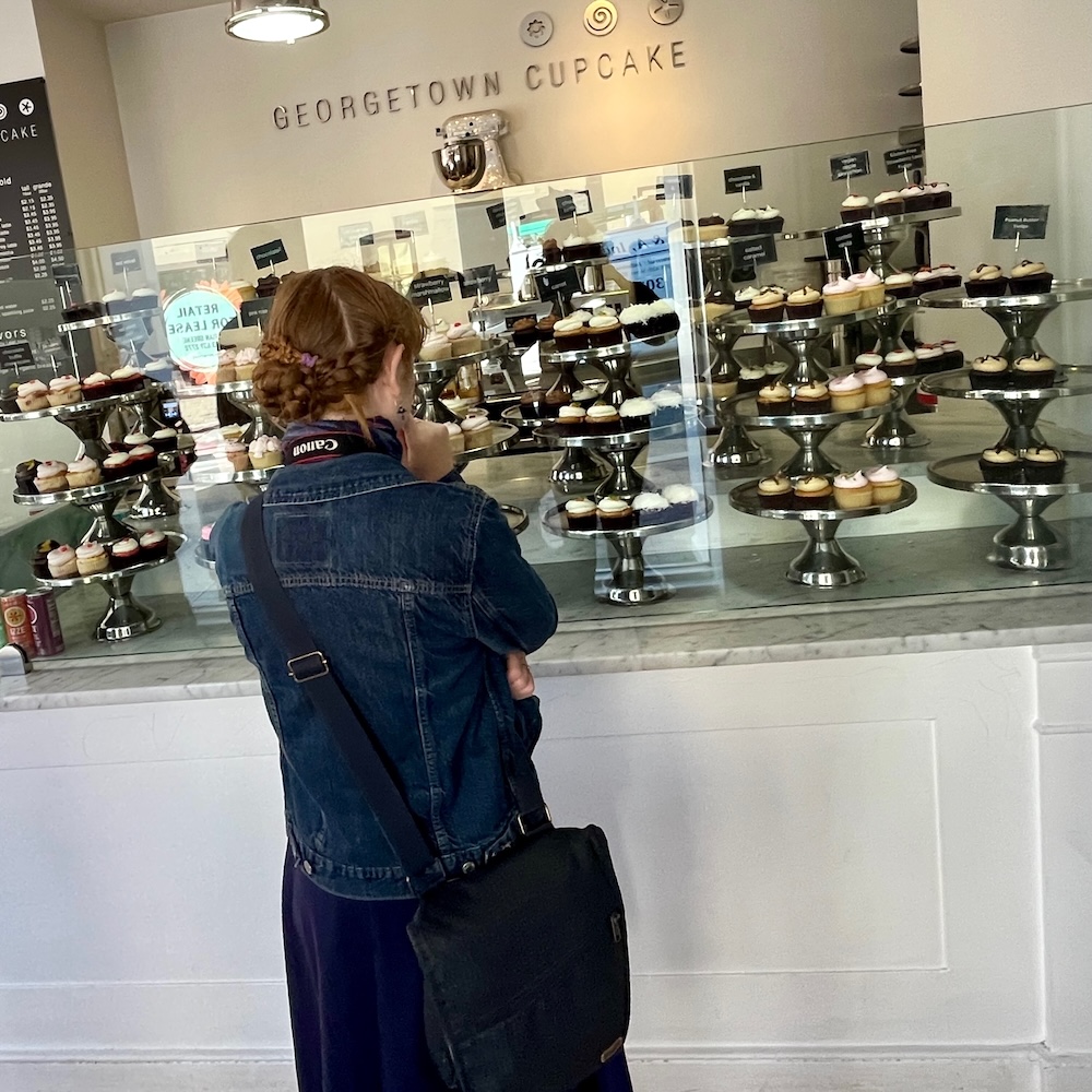 A teen girl ponders the main cupcake flavors stacked on tiered pastry trees at georgetown cupcake.