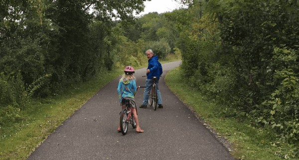 a dad and daughter pause in the bicyle ride on the  ashuwillticook rail trail in the berkshires