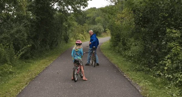 a dad and daughter pause in the bicyle ride on the  ashuwillticook rail trail in the berkshires