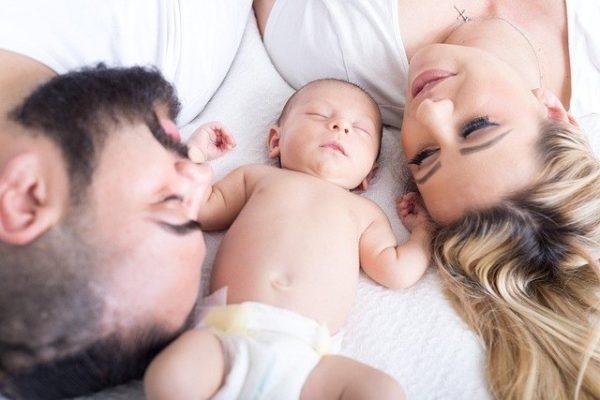 parents with sleeping baby between them.