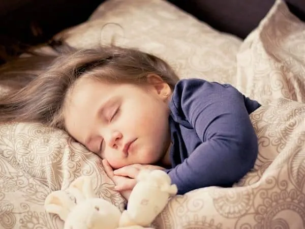 a toddler sleeping soundly in bed.