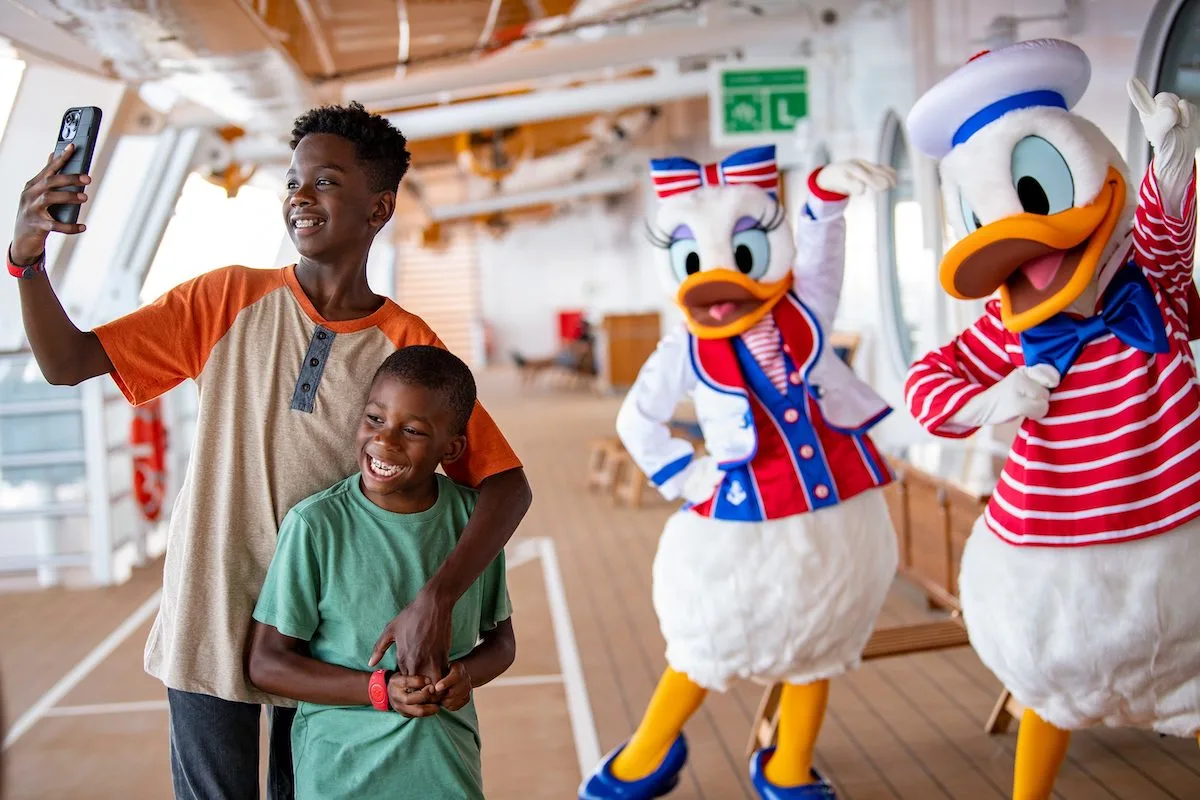 Two brothers take a selfie with Donald and Daisy Duck on a Disney cruise ship