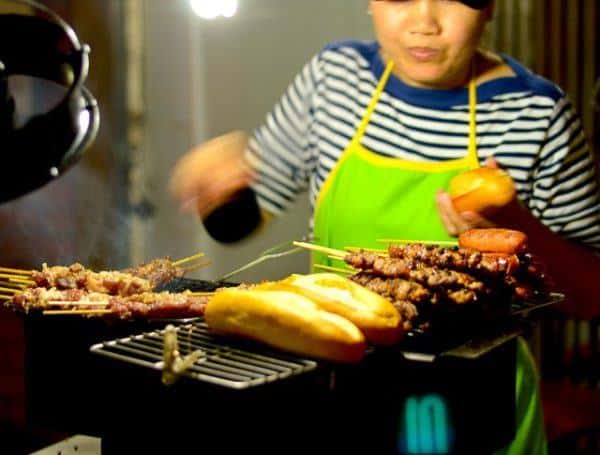 Street food is an essential part of any visit to vietnam. A woman grills bread and meafor bao.