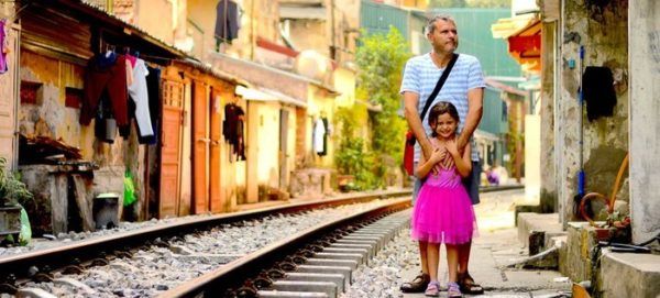 This railway village is a unique place in hanoi. A dad and daughter stand between the tracks a nd houses.