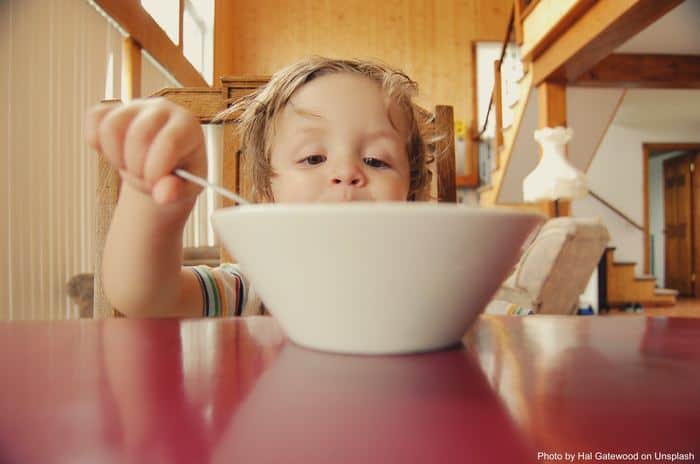 A boy eats a bowl of something he likes