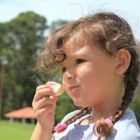 keeping kids healthy and well-fed on vacation is a challenge; girl eating sweets outdoors