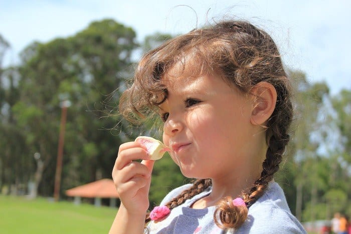 keeping kids healthy and well-fed on vacation is a challenge; girl eating sweets outdoors