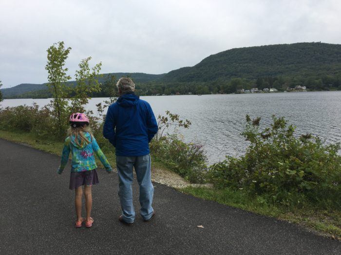a dad and daughter pausing along a rail trail to admire the berkshire mountains and a lake