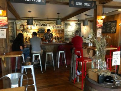 people sitting at the bar in the wood-paneled tasting room at hewn spirits