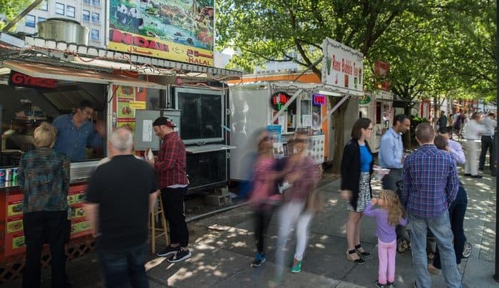 People cluster at a food truck court in portland