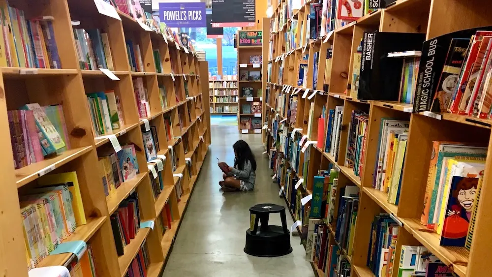 48 Hours In Portland, Or: 15 Things To Do, See &Amp; Eat With Tweens &Amp; Teens A girl sits in the rose room at powell's city of books, which has a huge selection of tween and teen favorites.