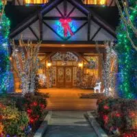 The Inn at Christmas Place lines its front walk and entrance with trees with blue, green and white lights, plus plenty of pine