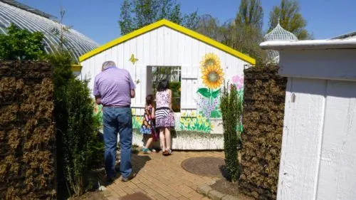 a dad and two girls explore a play shed at a botanic garden. perks like members-only hours can be a good reason to get a botanic garden membership