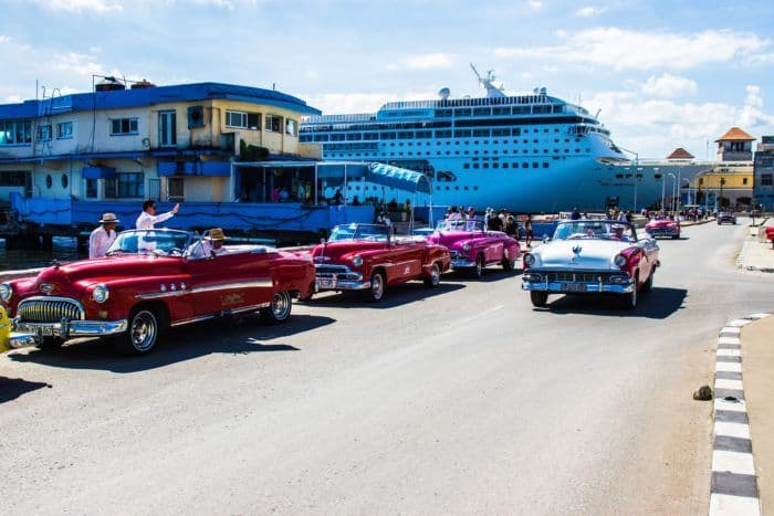 Classic cars park in front of havana's cruise ship port