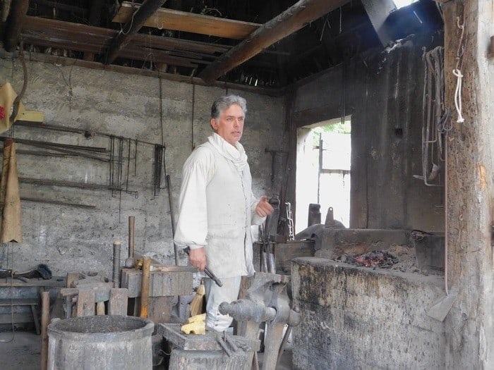 a volunteer does a blacksmithing demonstration in the colonial quarter