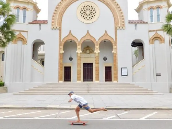 a barefoot skateboarder cruises by st. augustine's gilded-age church on the way to the beach.