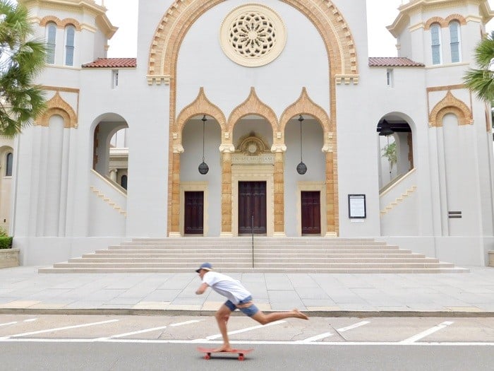 A barefoot skateboarder cruises by st. Augustine's gilded-age church on the way to the beach.