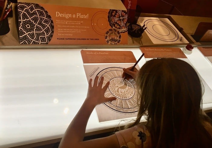 A child colors an elaborate stencil a the museum of international folk art.