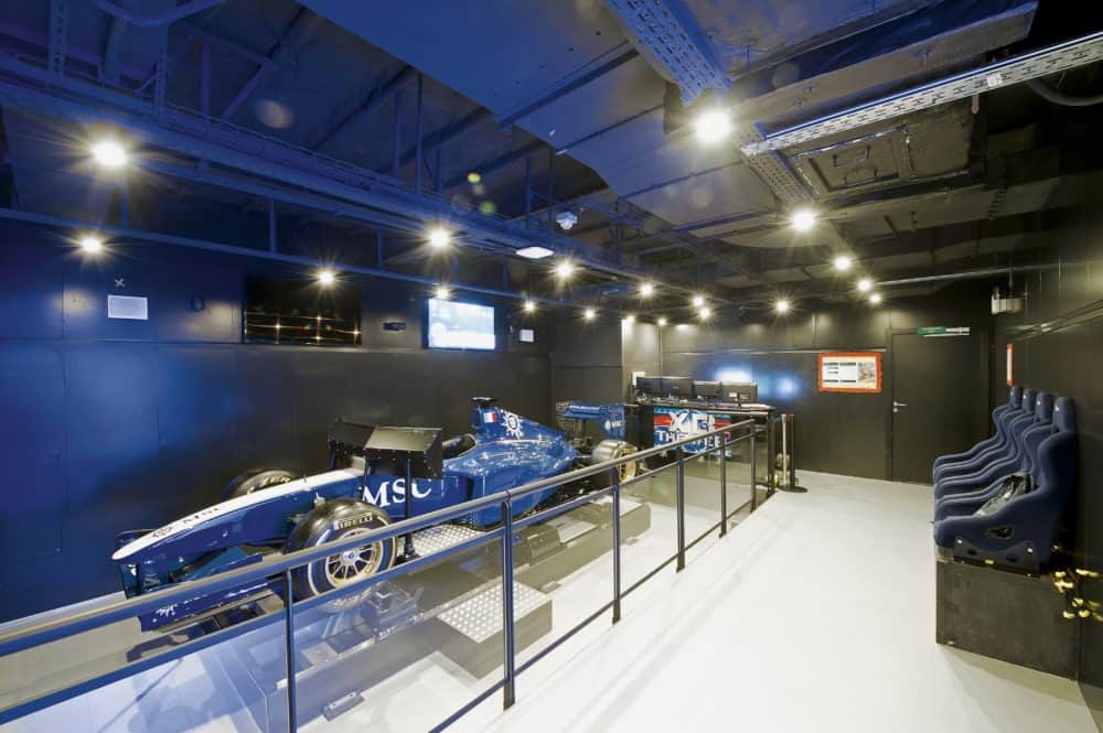 the sleek and high tech formula one racing simulator on the msc divina sits inside a small race car.