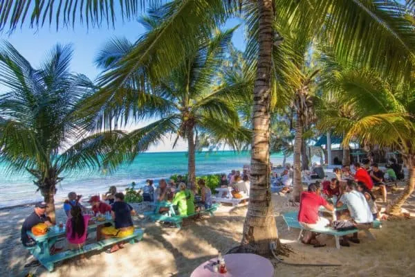 The Best Things To Do With Kids On 7 Caribbean Islands people eating at picnic tables in the sand at da conch bart on tci.