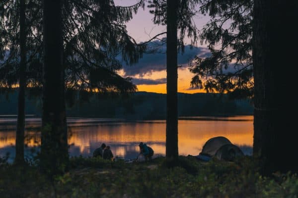 A family camping by a lake at dusk