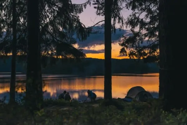 a family camping by a lake at dusk