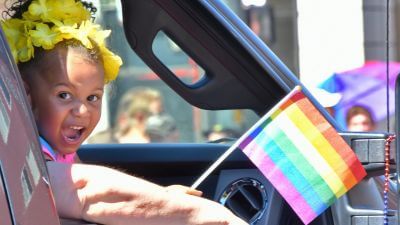 a toddler waves a gay pride flag in denver's annual parade