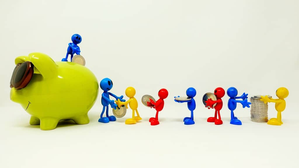 A tiny family passing along coins to put in a piggy bank that is bigger than they are.