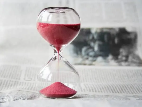 Save For Your Dream Vacation In 5 Easy Steps an hourglass sitting on a newspaper.