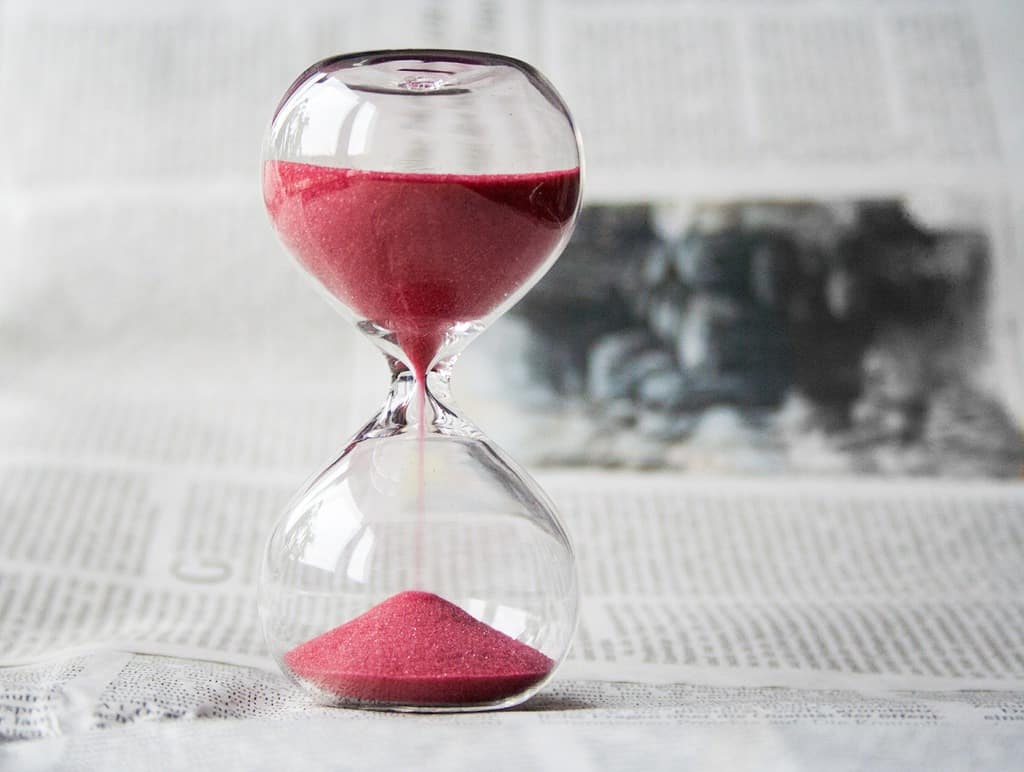 An hourglass with red sand running through it to mark time.